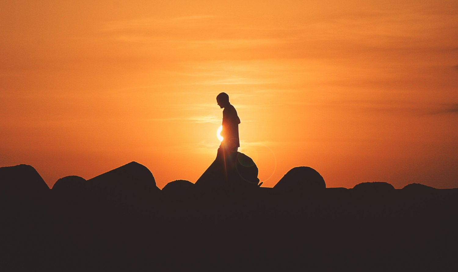 Silhouette of man standing in front of an orange sunset